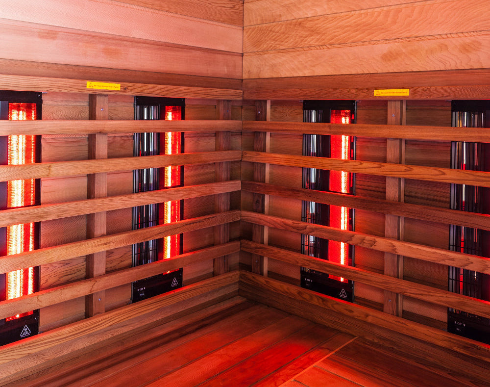 Infrared sauna with glowing red light panels and wood interior, designed for detox, muscle recovery, and inflammation relief through light therapy and heat exposure.